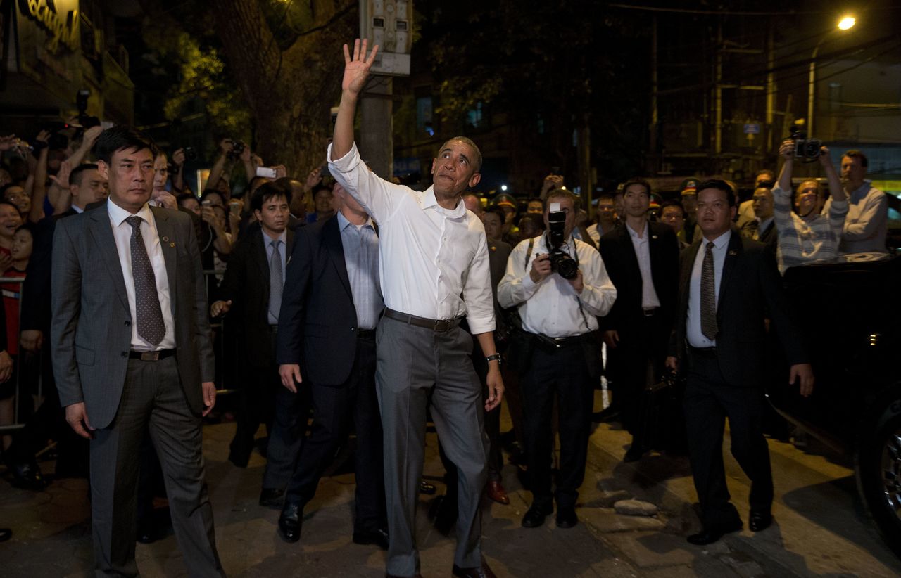 President Obama waves to the gathered crowd as he walks through Hanoi.