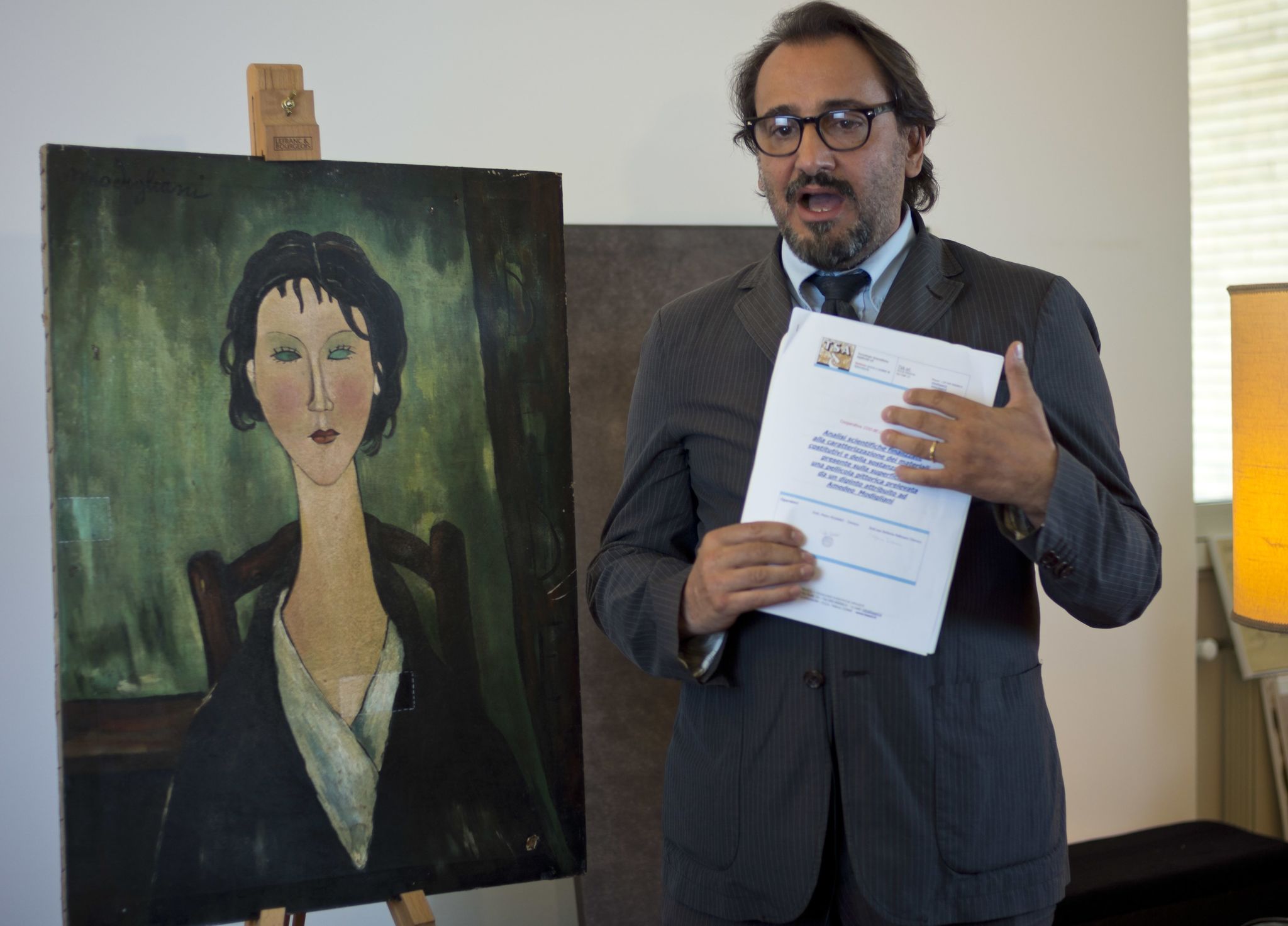Art historian Alberto D’Atanasio shows tests results Friday about an unidentified painting, at left, which is under investigation to determine whether it is an authentic work by Italian 20th century master Amedeo Modigliani.