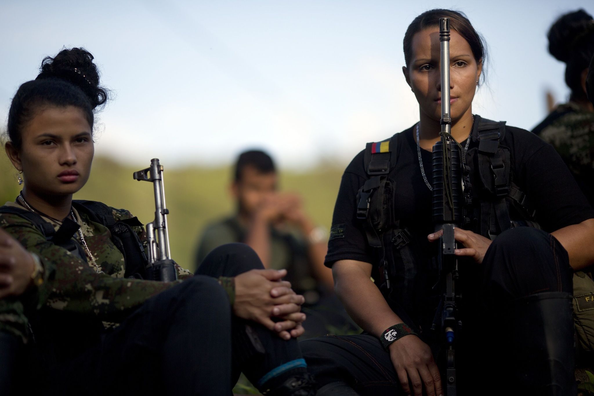 In this Jan. 4 photo, Juliana, 20, left, and Mariana, 24, rebel soldiers for the 36th Front of the Revolutionary Armed Forces of Colombia, or FARC, listen to a commander speak on the peace negotiations between the rebels and the Colombian government, in a hidden camp in Antioquia state, in the northwest Andes of Colombia. Colombian President Juan Manuel Santos said Tuesday that his government may reach an agreement on a bilateral ceasefire with leftist rebels as early as this week.
