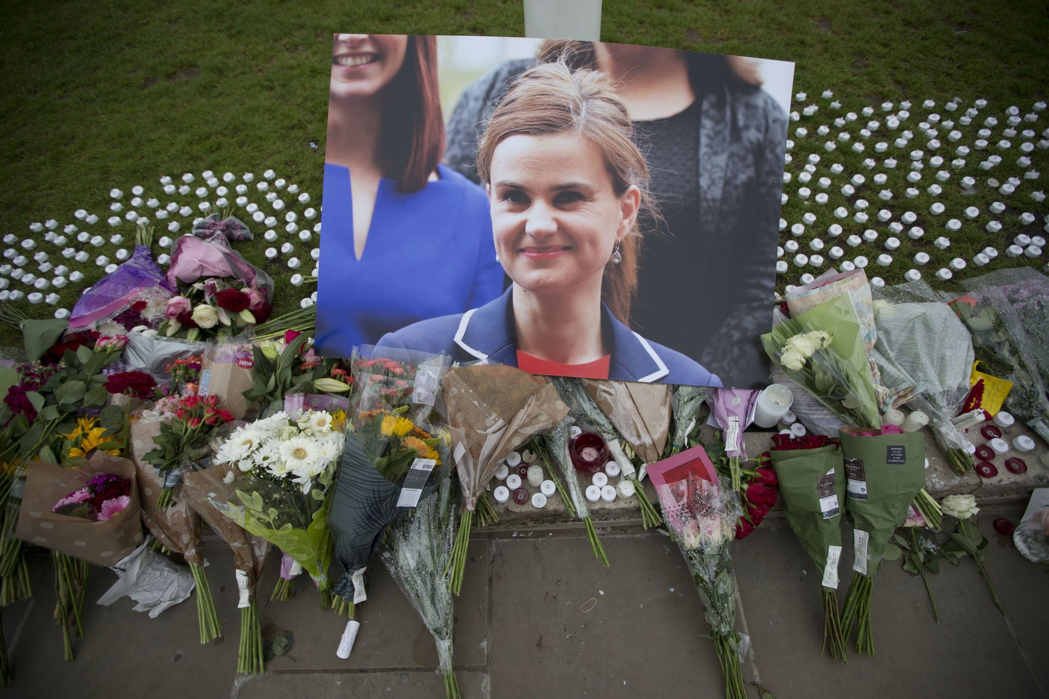 An image and floral tributes for Jo Cox are displayed on Parliament Square outside the House of Parliament in London on Friday, after the 41-year-old British member of Parliament was fatally injured Thursday in northern England.