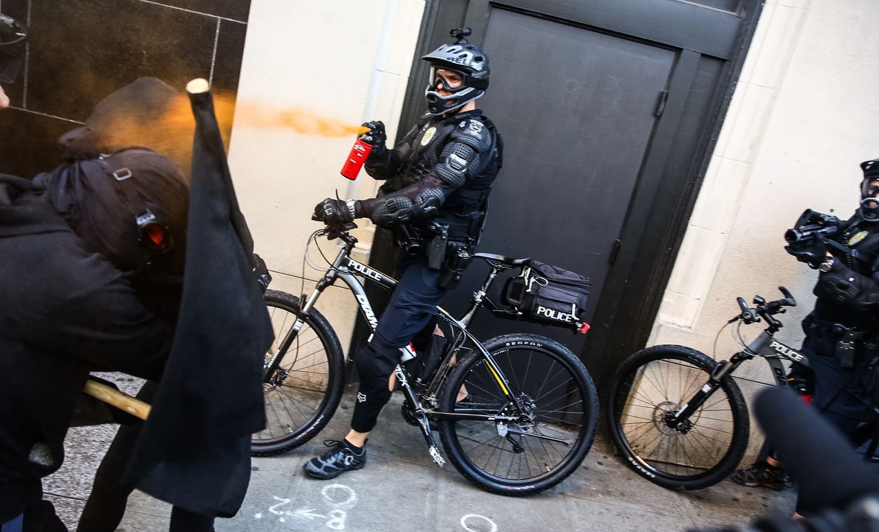 A police officer uses pepper spray during a May Day protest Sunday in Seattle.