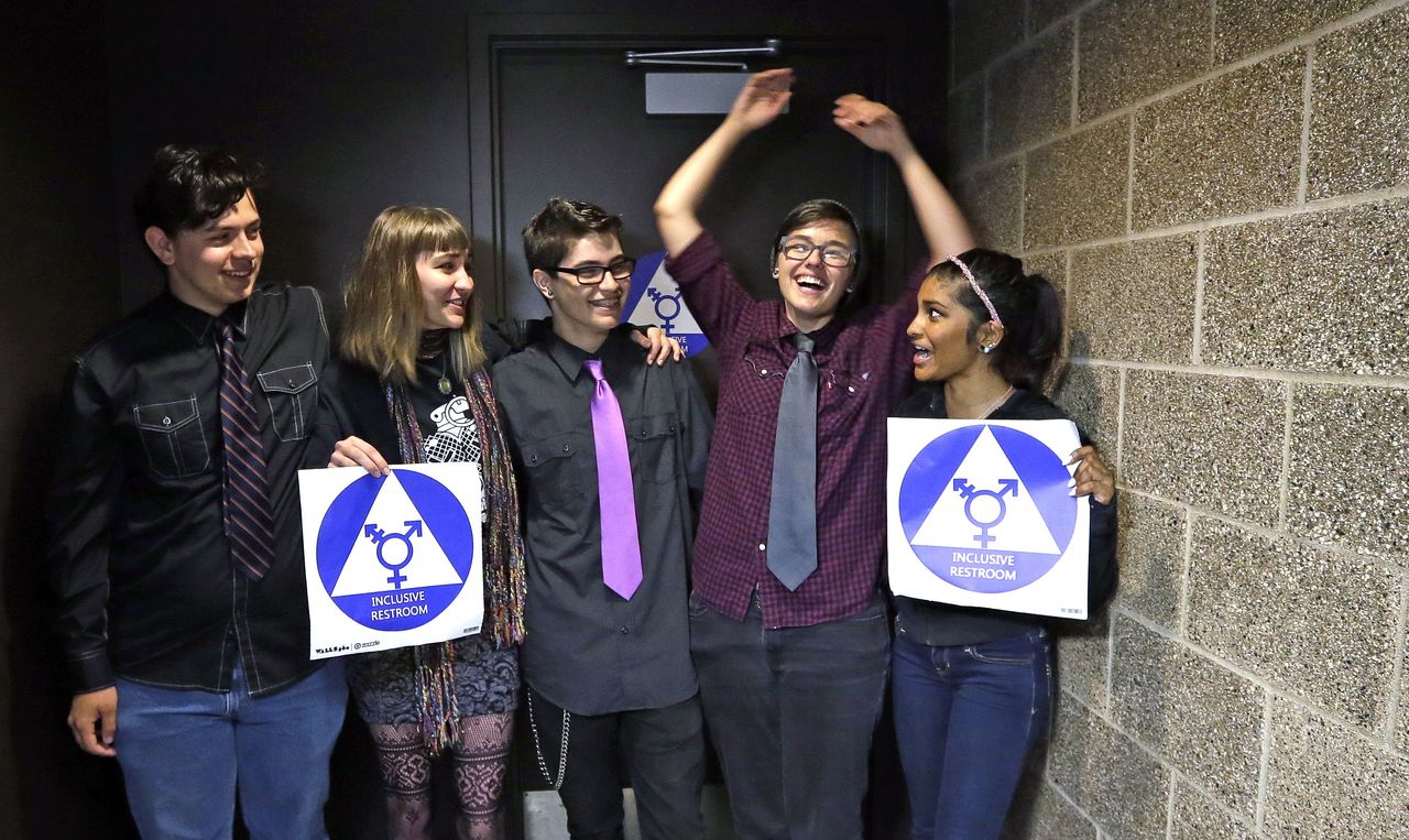 Destin Cramer (second right) embraces friends from the school’s Gender Awareness Group as they pose for a photo Tuesday at the opening of a gender neutral bathroom at Nathan Hale High School in Seattle.