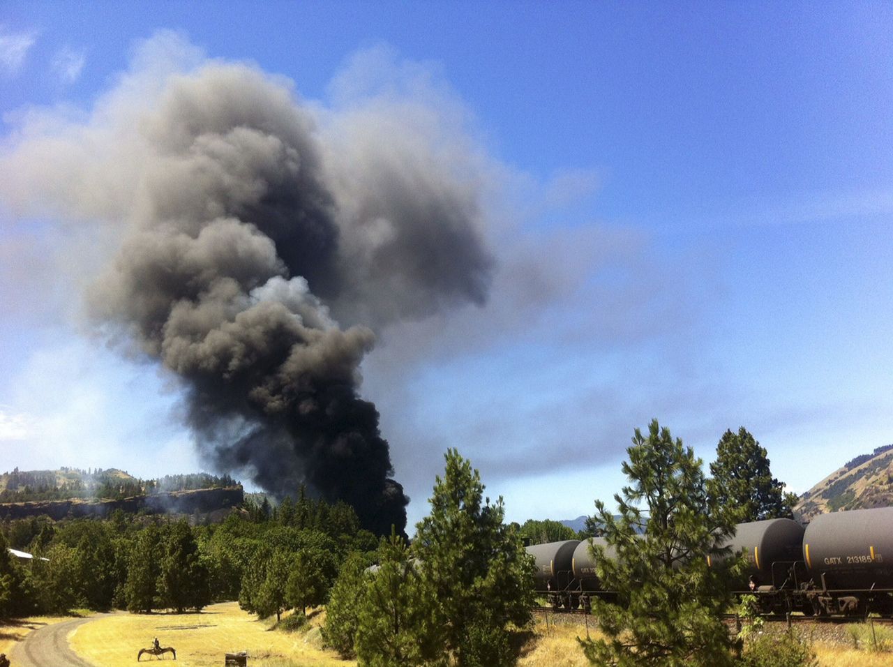 A train towing cars full of oil sends up a plume of smoke after derailing Friday near Mosier, Oregon, by the scenic Columbia River Gorge.