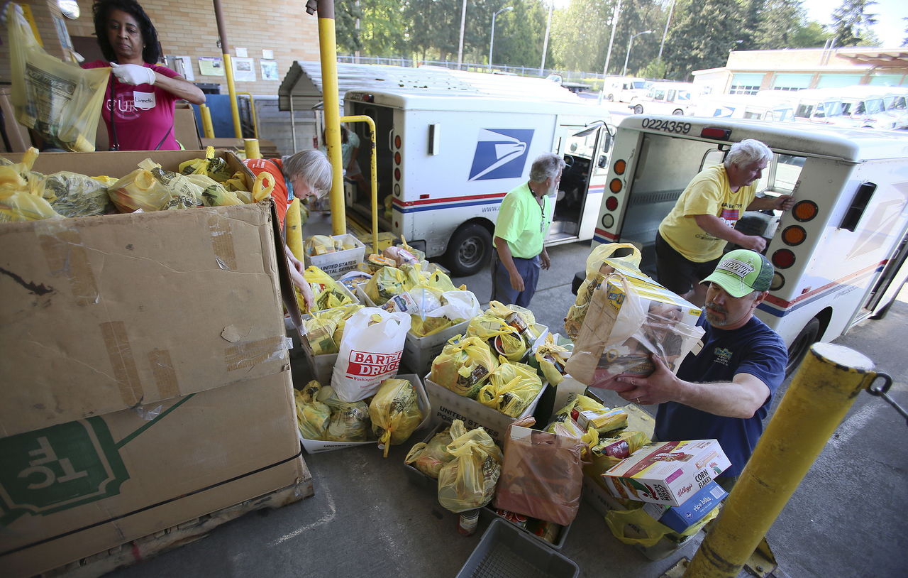 Volunteers unload postal vehicles full of food donations at the Lynnwood Post Office during last year’s Letter Carrier’s Food Drive in Snohomish County.