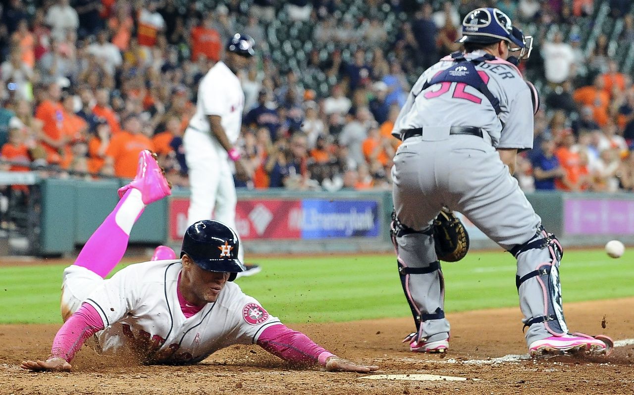 The Astros’ George Springer slides past Mariners catcher Steve Clevenger, scoring on Carlos Correa’s RBI single in the seventh inning of Sunday’s game.