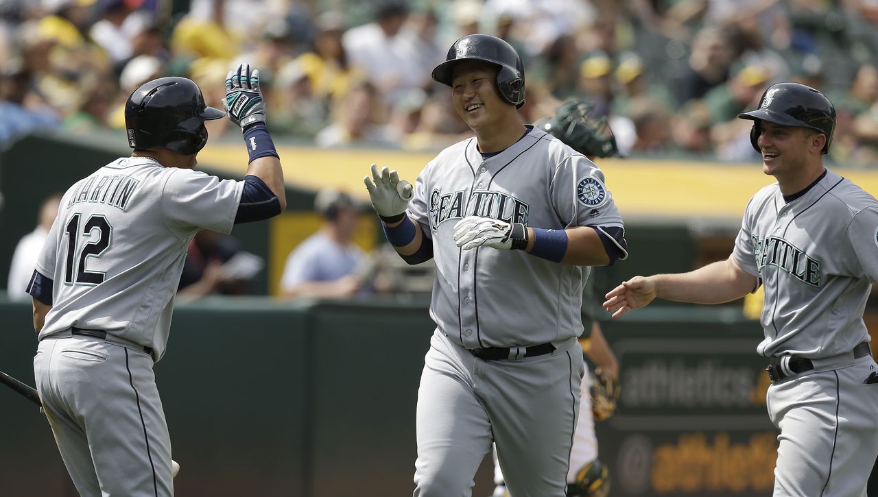 The Mariners’ Dae-Ho Lee (center) is congratulated by Leonys Martin (12) and Kyle Seager (right) after hitting a two-run home run in the seventh inning to give Seattle a 9-8 lead.
