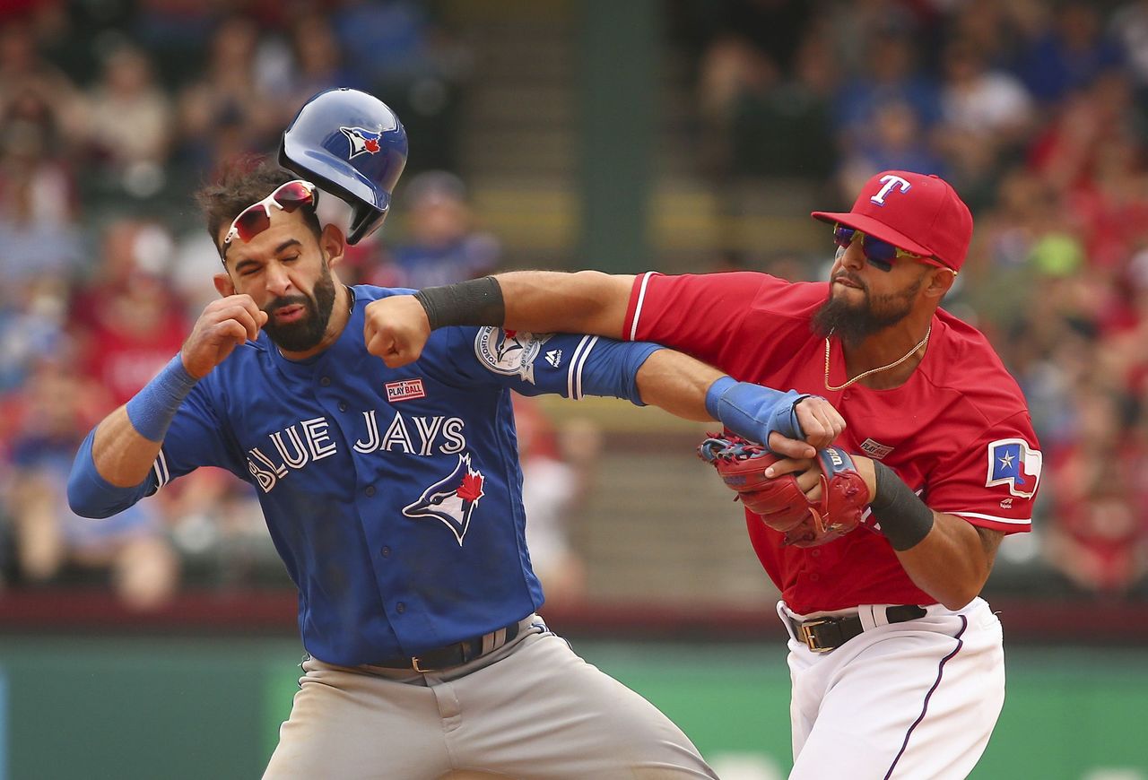 Rangers second baseman Rougned Odor (12) punches the Blue Jays Jose Bautista (19) after Bautista slid into second base in Sunday’s game in Arlington, Texas.