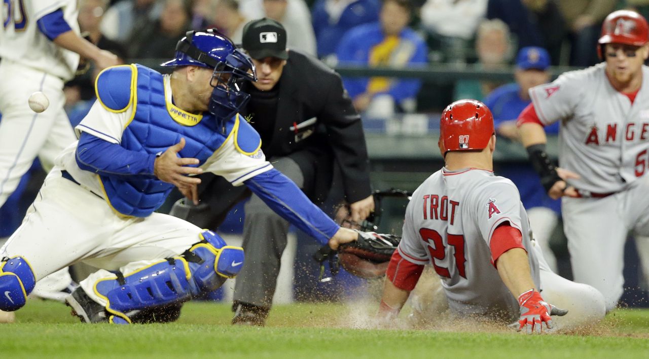 Ted S. Warren / Associated Press The ball eludes Mariners catcher Chris Iannetta as the Angels’ Mike Trout scores in the eighth inning of Sunday’s game at Safeco Field in Seattle.