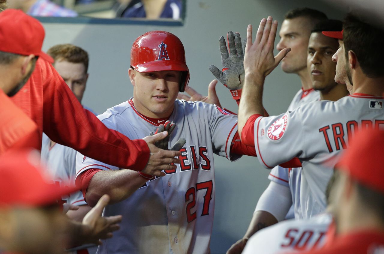 The Angels’ Mike Trout (center) is greeted in the dugout after he scored on a single by Daniel Nava during the fourth inning of a game against the Mariners on Friday in Seattle.