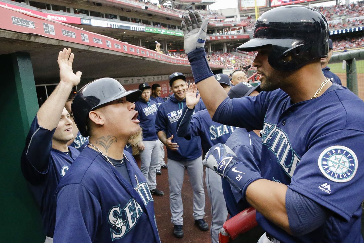 The Mariners’ Franklin Gutierrez (right) celebrates with Felix Hernandez in the Seattle dugout after hitting a three-run home run off Reds starting pitcher John Lamb in the fourth inning of Saturday’s game.