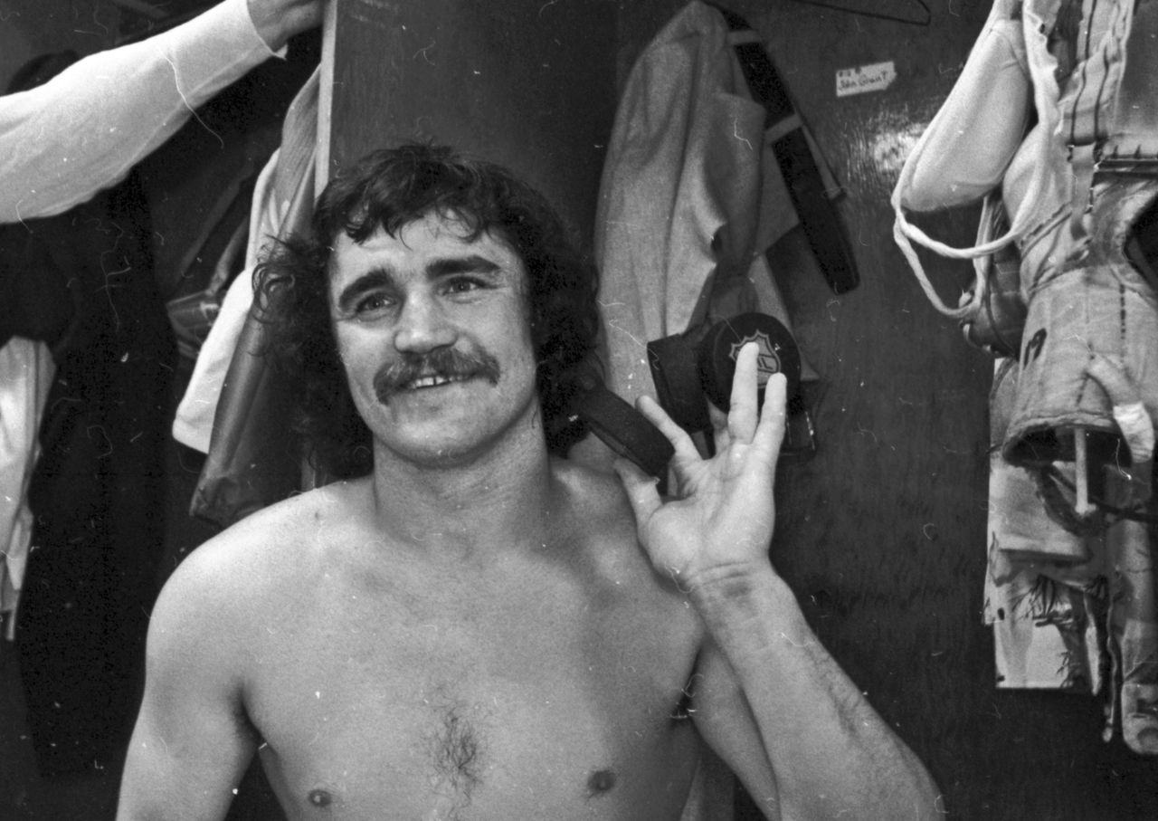 In this April 13, 1975, photo, Philadelphia Flyers’ Rich MacLeish smiles as he holds up three pucks in the locker rom after scoring three goals against the Toronto Maple Leafs in an NHL game in Philadelphia. MacLeish, who starred for the Broad Street Bullies teams of the Flyers that won the Stanley Cup in 1974 and 1975, has died, the team announced Tuesday. He was 66.