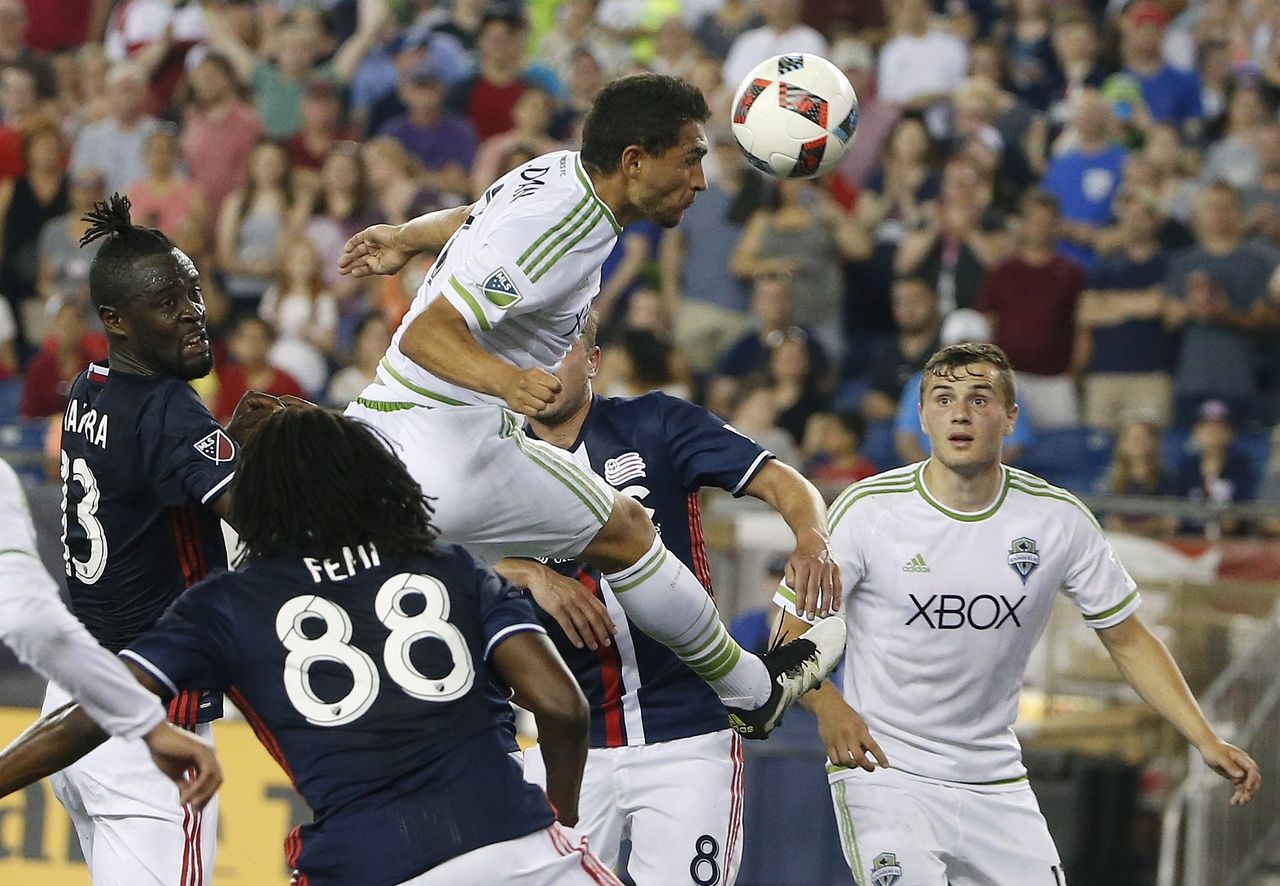 The Sounders’ Cristian Roldan (top) heads the ball in front of the Revolution’s Femi Hollinger-Janzen (88) during the second half of a match Saturday in Foxborough, Mass.