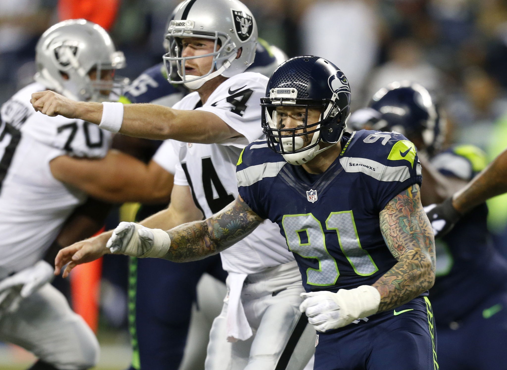 The Seahawks’ Cassius Marsh (91) pressures Raiders quarterback Matt McGloin (14) during a preseason game this past season in Seattle. Marsh is competing to be Seattle’s starting strong-side linebacker this season.