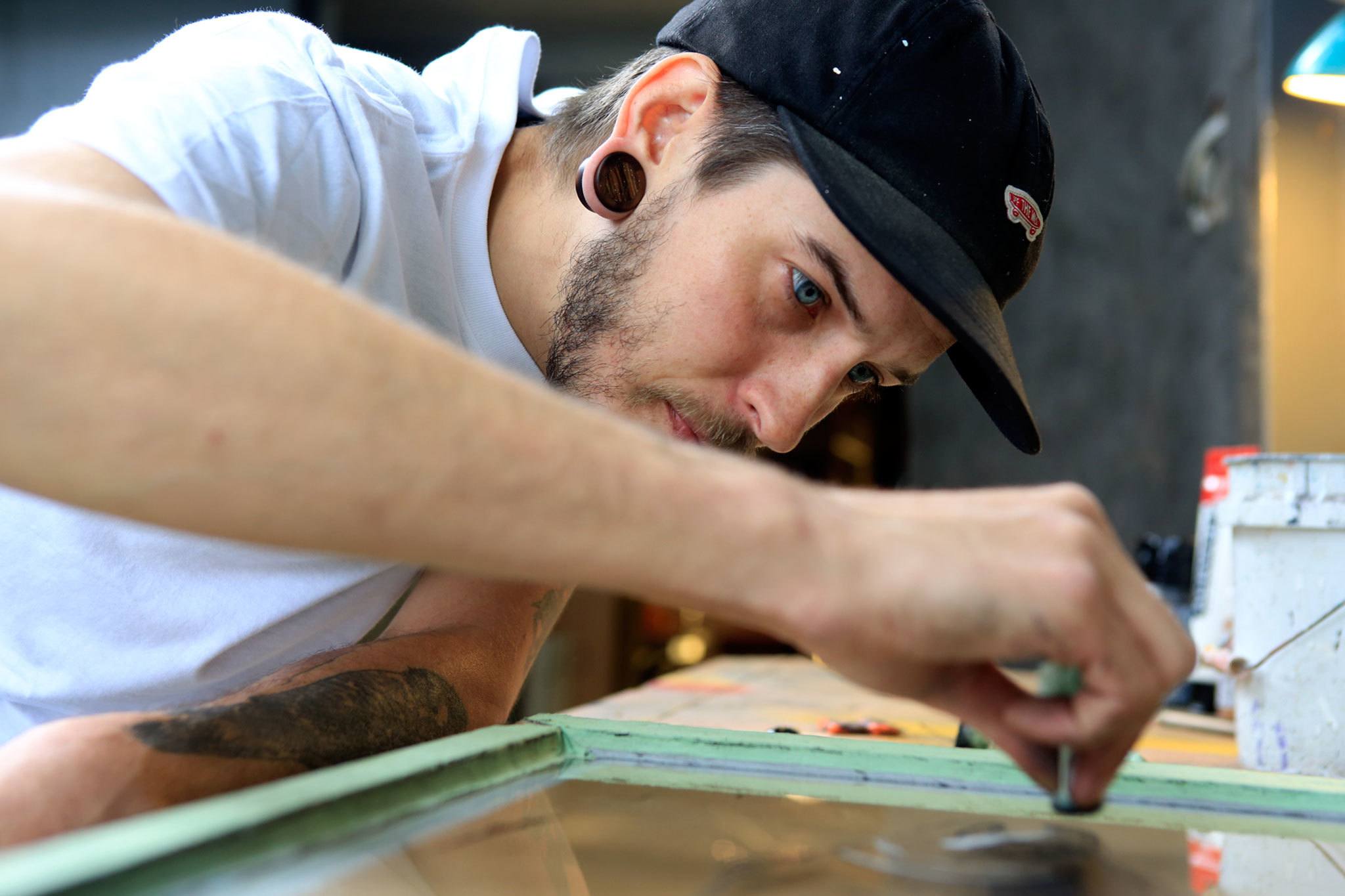 Kevin Clark / The Herald                                Artist Evan Peterson paints on reclaimed glass windows in reverse, creating the foreground first and then thebackground. Peterson is this year’s poster artist at the Fresh Paint: Festival of Artists at Work.