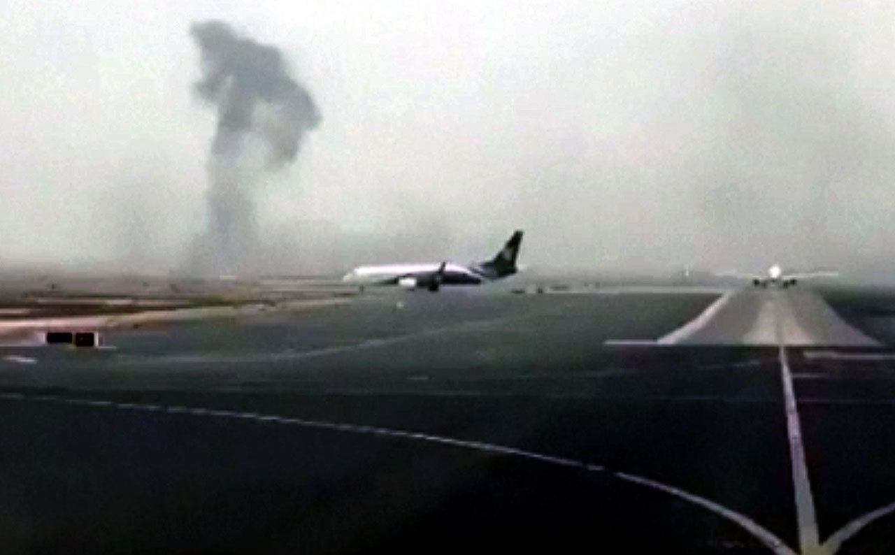 This image from a video shows smoke rising after an Emirates Boeing 777 crash-landed at Dubai International Airport on Wednesday. The plane at right was unaffected. (Hayen Ayari via AP)