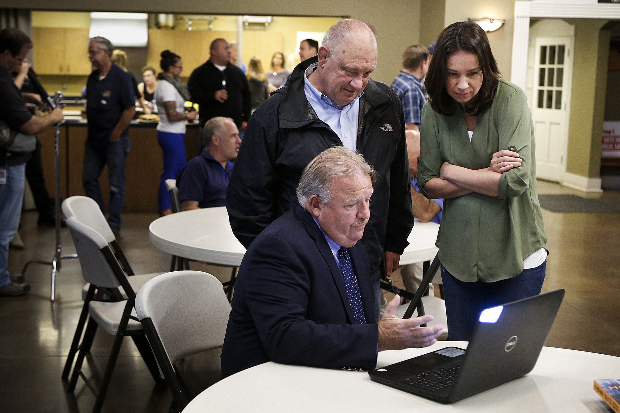 Snohomish County Sheriff Ty Trenary looks at initial voting results for Proposition 1 with Snohomish County Councilman Brian Sullivan and campaign manager Brooke Davis (right) at a gathering for supporters of the proposition at Everett Firefighters Hall on Tuesday night. (Ian Terry / The Herald)