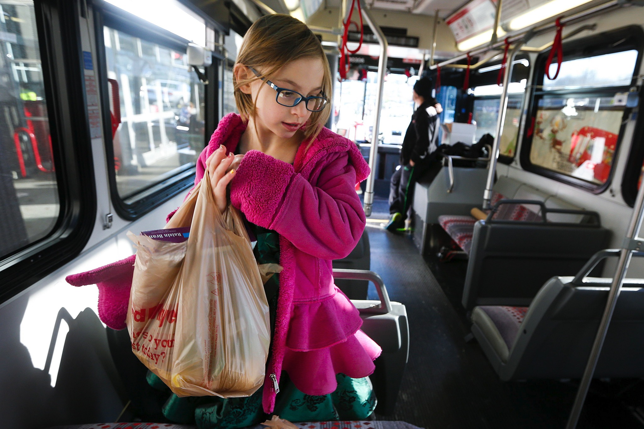Isabeau Prettyman, 8, of Marysville, organizes donations on an Everett Transit bus used for the annual Stuff a Bus Foodand Toy Charity drive at Fred Meyer in Everett in November 2015. The nonprofit Everett Public Schools Foundation ishosting its seventh annual Stuff the Bus for Kids campaign on Aug. 12-14 at three local stores. (Herald photo)