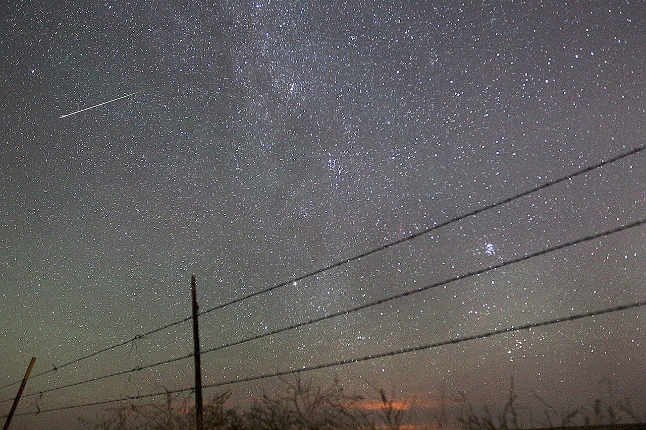 In this Aug. 13, 2013 photo, a meteor streaks past the faint band of the Milky Way galaxy above the countryside north of Cheyenne, Wyoming, during a Perseids meteor shower. On Thursday night and early Friday morning, the Perseid meteor shower is expected to peak with double the normal number of meteors. Scientists call this an outburst, and they say it could reach up to 200 meteors per hour. (AP Photo/The Wyoming Tribune Eagle, Blaine McCartney, file)