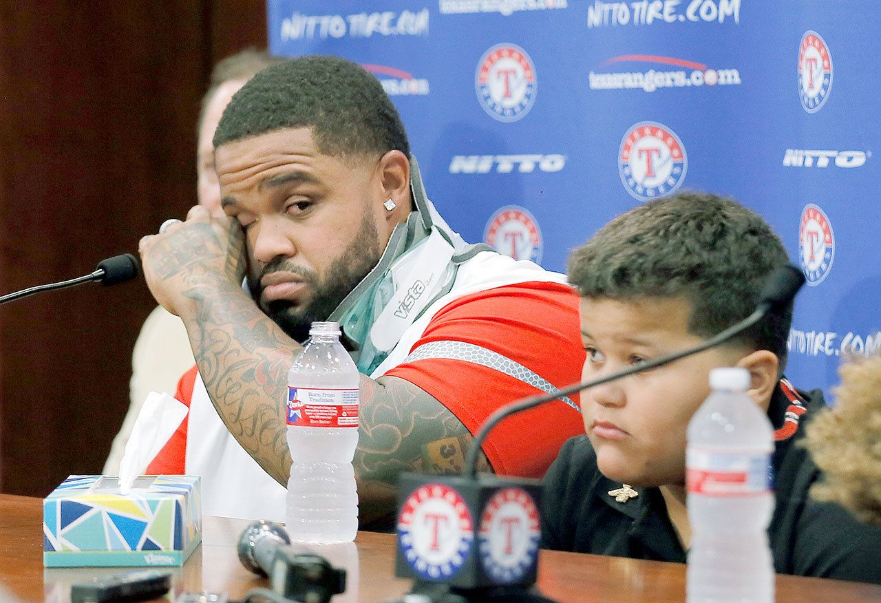 Texas’ Prince Fielder (left) wipes his eyes as he sits by his son Haven during a news conference at which the 32-year-old slugger announced he won’t be able to come back from a second neck surgery. (AP Photo/Tony Gutierrez)