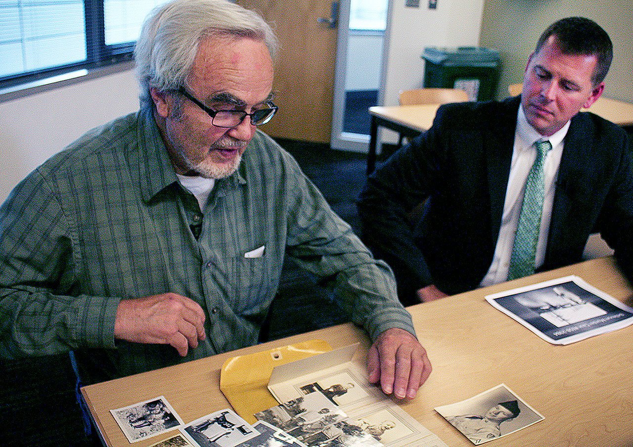 Lee Sundholm, left, looks at photos of his late brother, Loren Sundholm, as Detective Shelby Shearer looks on. (Allison DeAngelis / Bellevue Reporter)