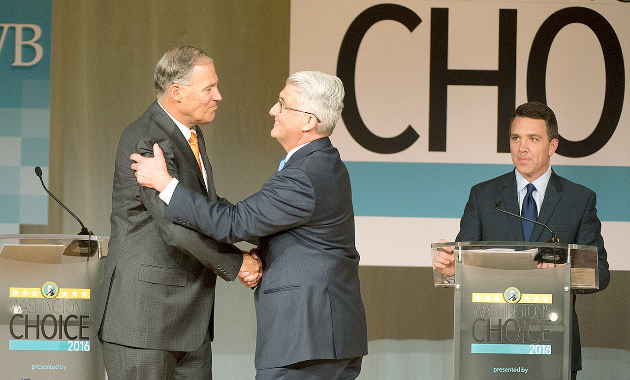 Washington Gov. Jay Inslee (left) shakes hands with challenger Bill Bryant before their two debate at Spokane Falls Community College on Wednesday. Moderator Sean Owsley of KHQ-TV is at right. (Jesse Tinsley/The Spokesman-Review via AP)