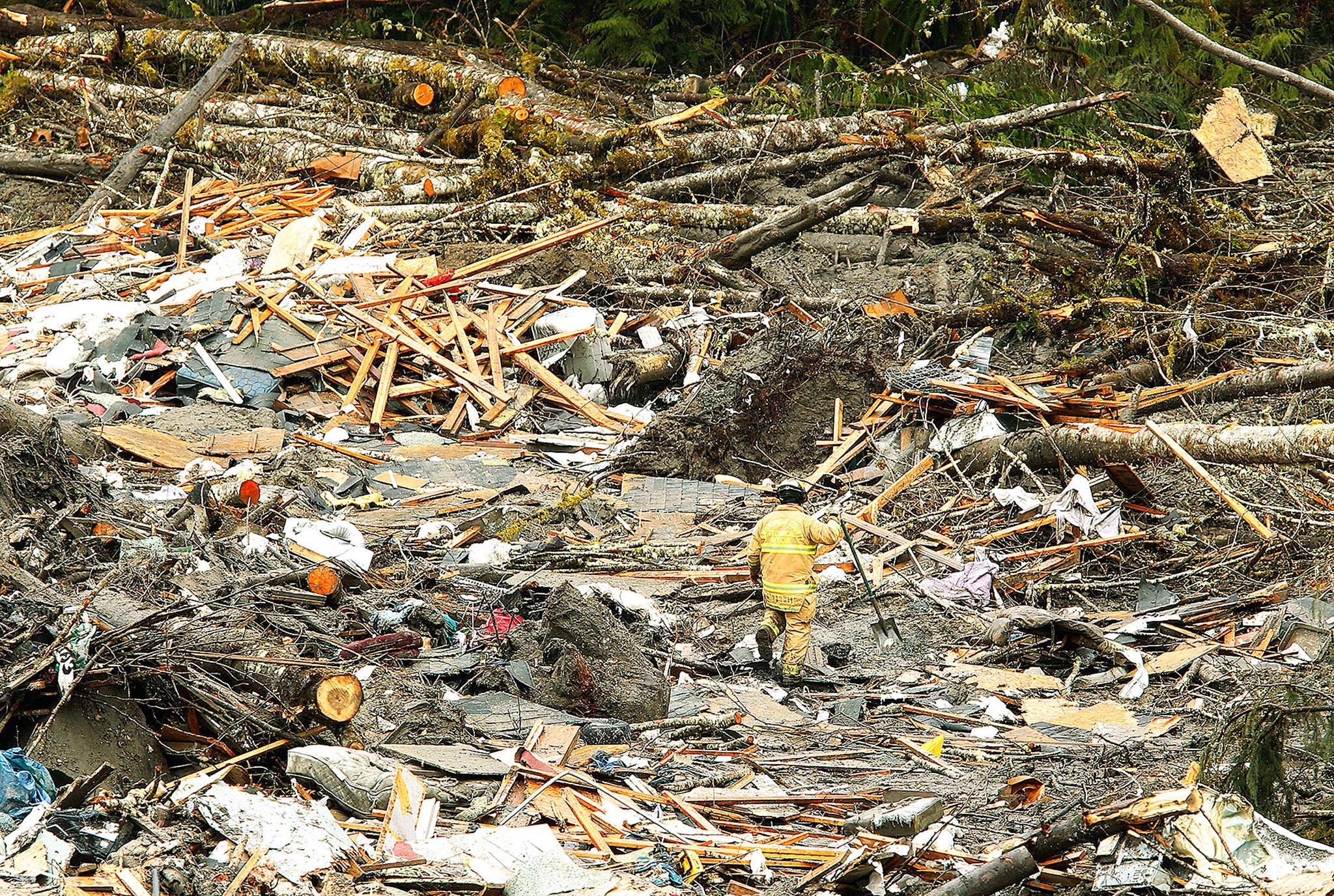 Five days after the disaster in March 2014, a firefighter searches rubble at the Oso mudslide. (Mark Mulligan / The Herald)