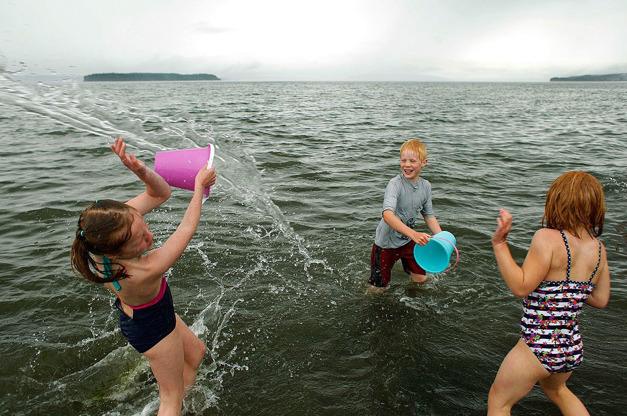 Eric Magelsen lets loose with a bucket of water on his cousin, Rachel Magelsen (left) during a visit to Jetty Island. The ferry to the island runs through Sept. 5. (Herald 2012 file photo)