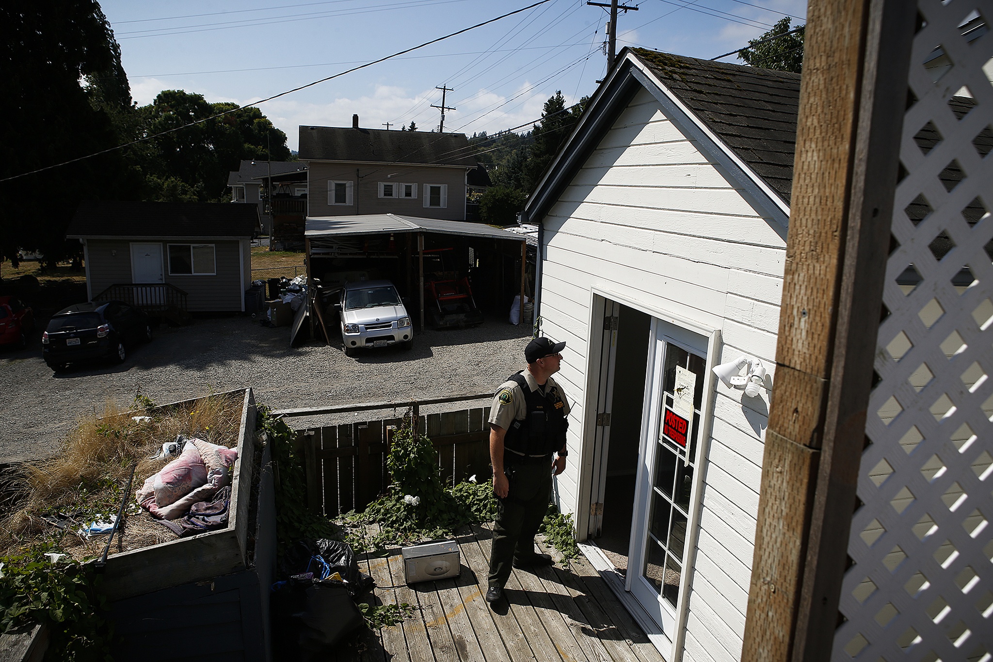 Snohomish County sheriff’s deputy Alex Ross looks around a property on South Third Avenue near Lowell while carrying out an eviction on Aug. 11. The residents had left the property by the time deputies arrived. (Ian Terry / The Herald)