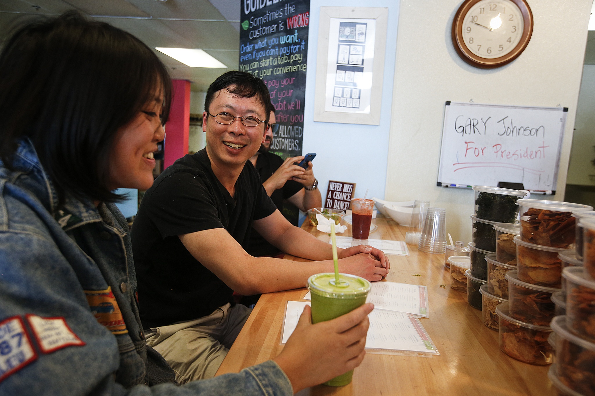 Alive Juice Bar owner Andrew Ho (center) chats with customers at his Ballinger Way store July 20. Ho asks that customers don’t form lines, but rather say their order as soon as they decide. (Ian Terry / The Herald)