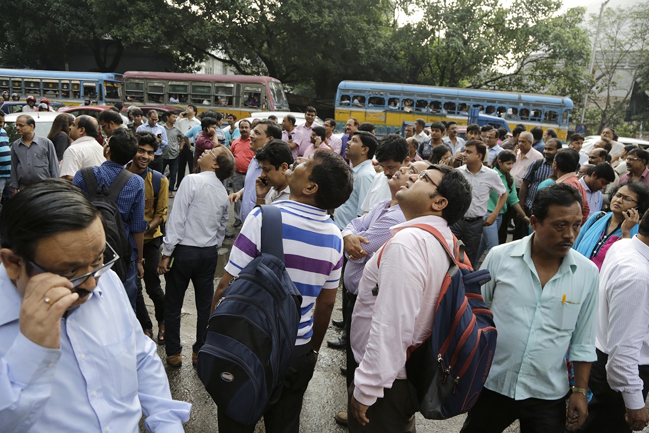 People stand in the street after they rushed out of their offices following tremors in Kolkata, India, on Wednesday. A powerful earthquake with a preliminary magnitude of 6.8 shook central Myanmar on Wednesday, knocking glasses off tables and sending people running out of buildings in the country’s largest city. The U.S. Geological Survey said the quake was centered about 15 miles west of Chauk, an area west of the ancient capital of Bagan. (AP Photo/Bikas Das)