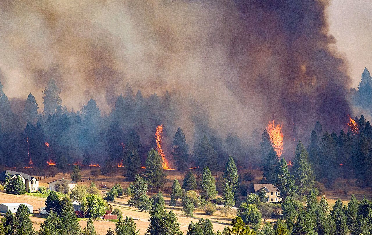 A fast-moving wildfire approaches homes on the north side of Beacon Hill on Sunday in Spokane. A series of fires started Sunday afternoon amid high winds and temperatures in the 90s. (Colin Mulvany/The Spokesman-Review via AP)