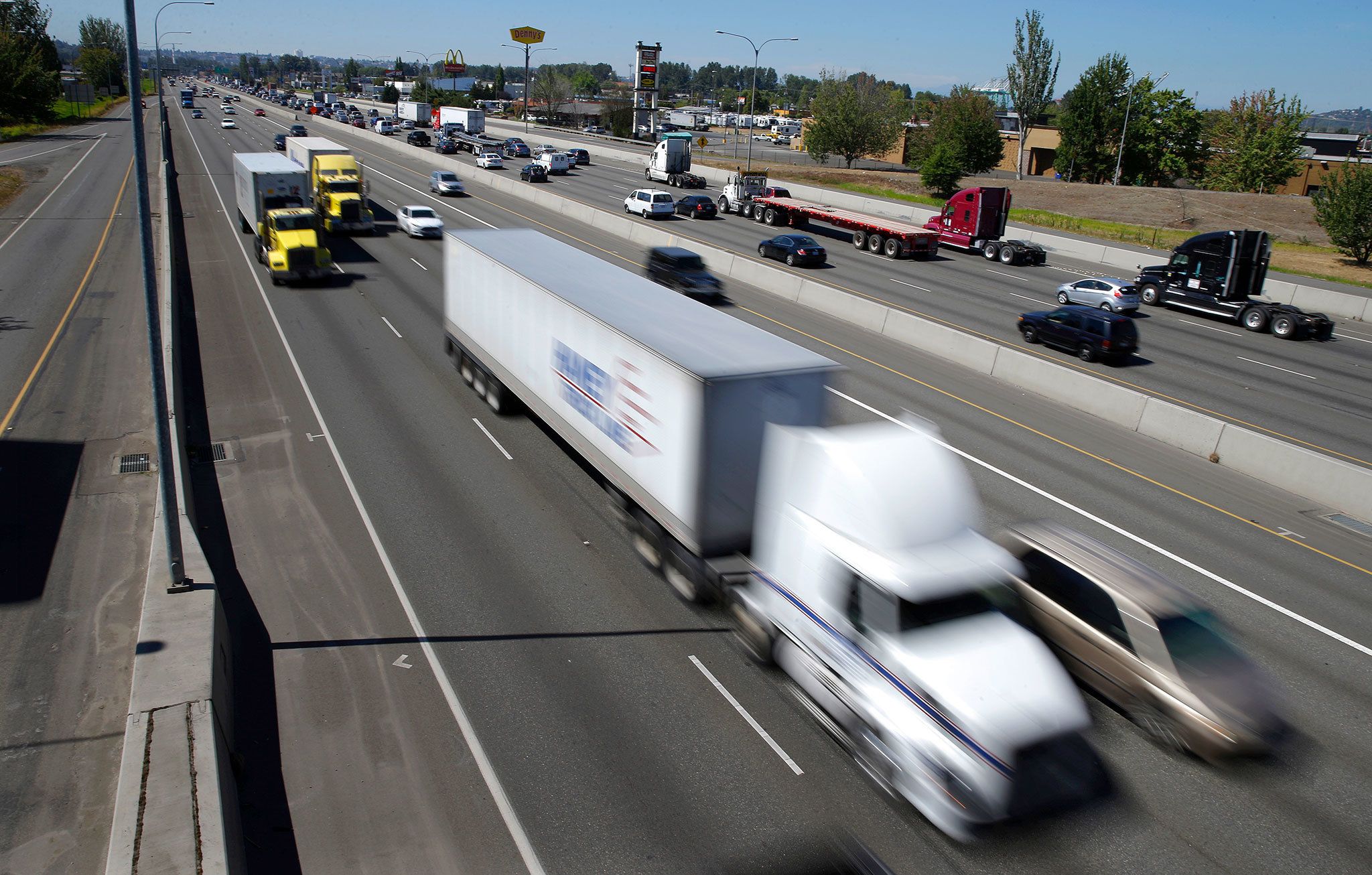 Truck and automobile traffic mix on I-5, headed north through Fife near the Port of Tacoma on Wednesday. The federal government wants to limit how fast trucks, buses and other large vehicles can drive on the nation’s highways. (AP Photo / Ted Warren)