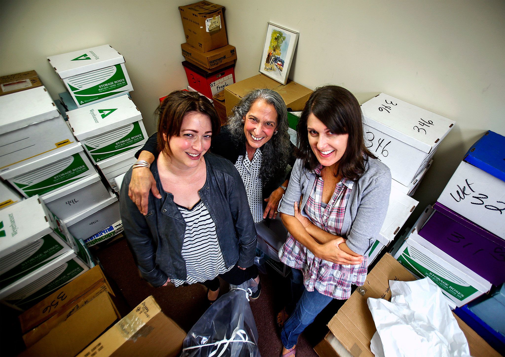 Volunteer coordinator Kim David (center), curator Amalia Kozloff (left) and registrar Heather Schaub (right) pause in one of the Everett Museum of History’s storage rooms with items they have carefully catalogued, wrapped and boxed in the Culmback Building basement. (Dan Bates / The Herald)