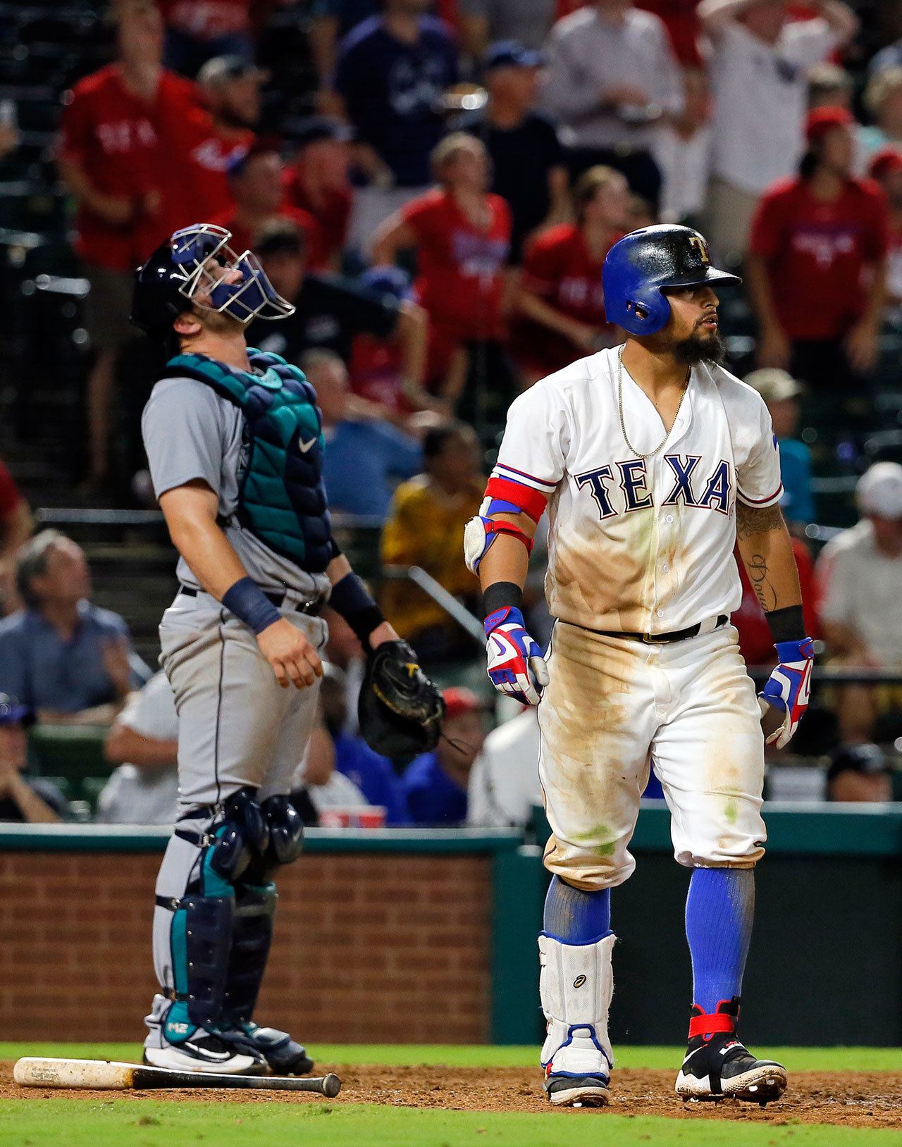 Mariners catcher Mike Zunino (left) looks skyward as the Rangers’ Rougned Odor watches his two-run home run in the ninth inning Tuesday in Arlington, Texas. The homer scored Adrian Beltre, giving the Rangers an 8-7 win. (AP Photo/Tony Gutierrez)