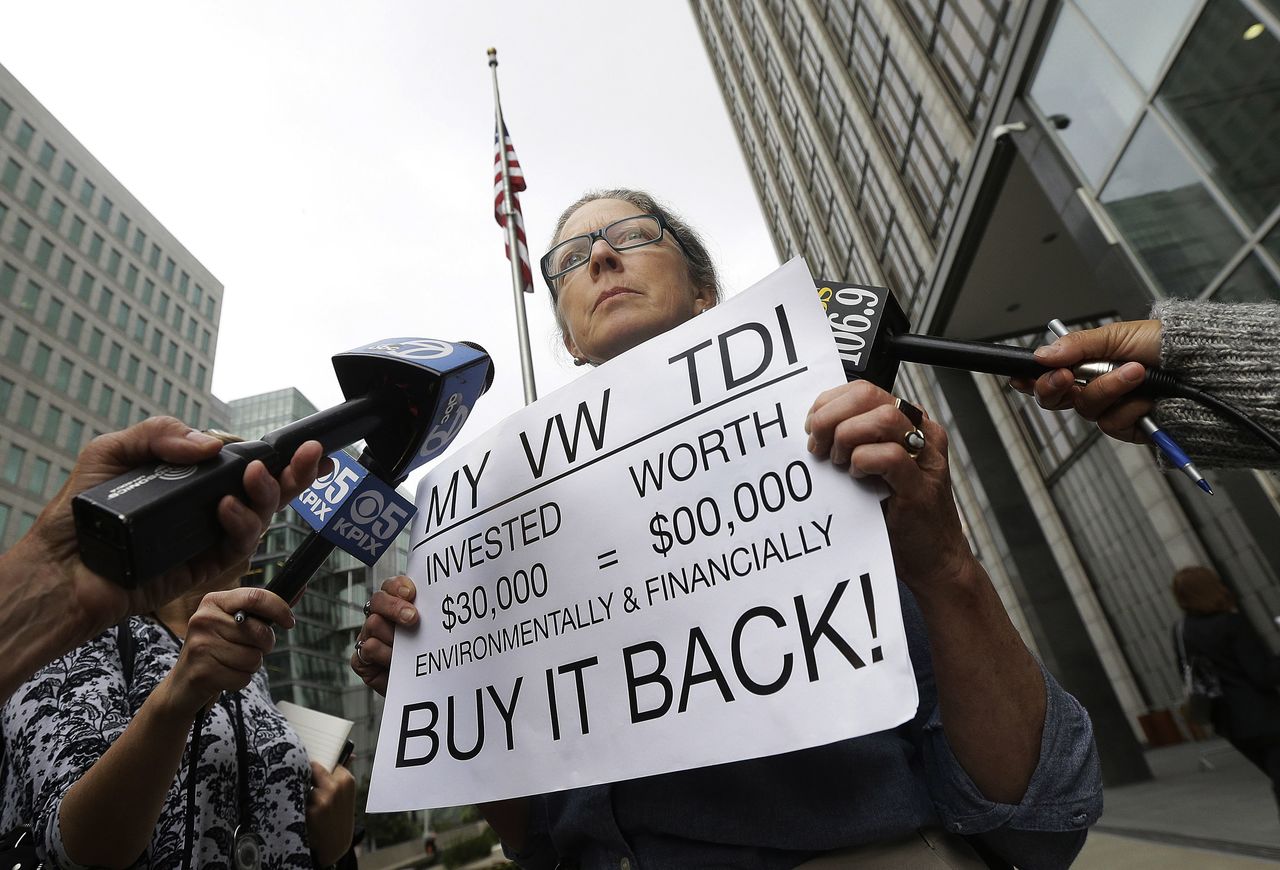 Joyce Ertel Hulbert, owner of a 2015 Volkswagen Golf TDI, holds a sign while interviewed outside of the Phillip Burton Federal Building in San Francisco on Thursday. An agreement will give consumers who bought nearly 600,000 Volkswagen vehicles rigged to cheat on emissions tests the option of having the automaker buy back the cars or fix them, a judge said Thursday.