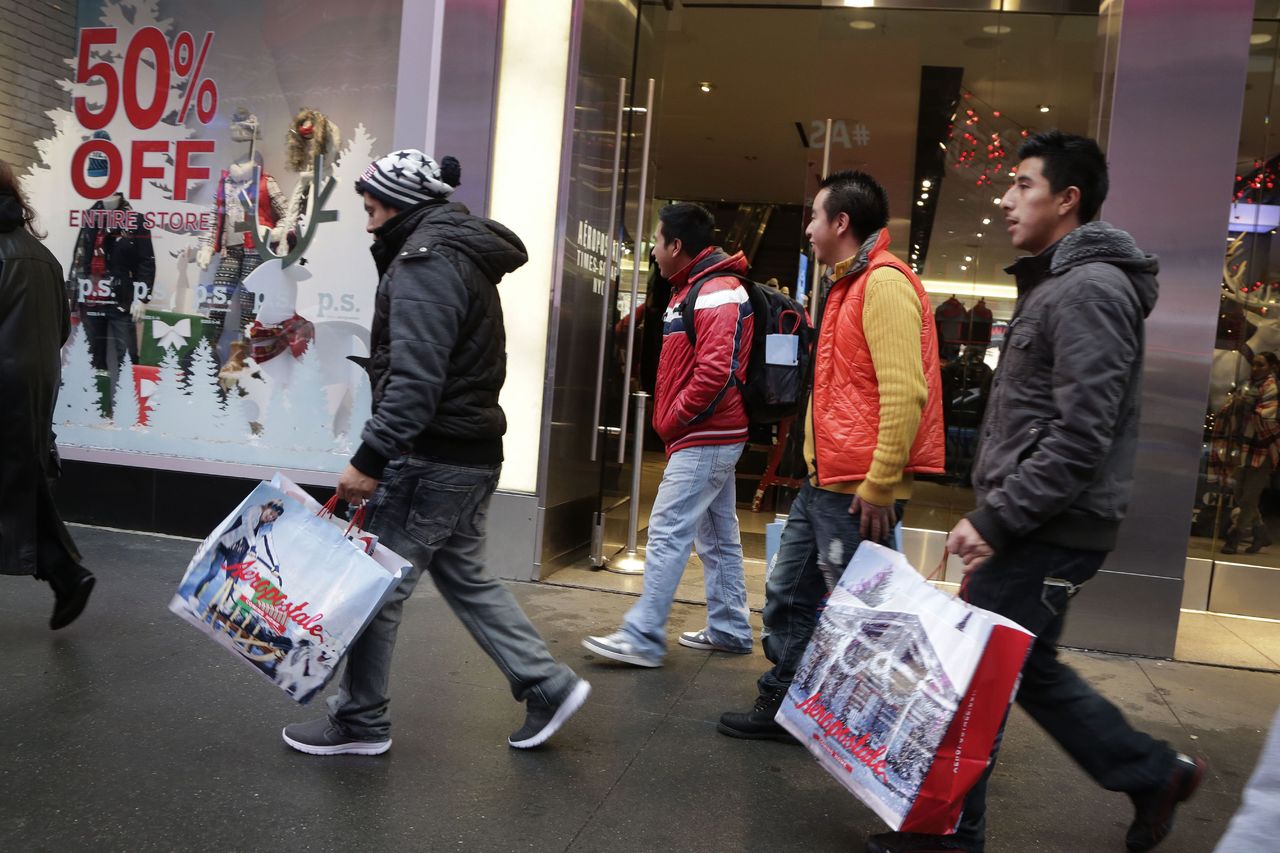 In this Dec. 2, 2015, photo, shoppers carry their shopping bags as they leave the Aeropostale clothing store in New York’s Times Square. On Monday, the Commerce Department issues its December report on consumer spending, which accounts for roughly 70 percent of U.S. economic activity.