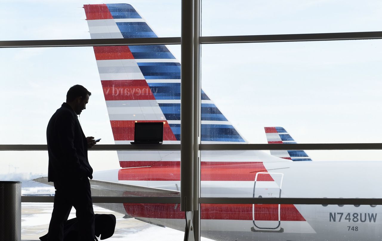 A passenger talks on the phone as American Airlines jets sit parked at their gates at Washington’s Ronald Reagan National Airport on Jan. 25. After 15 years of cutbacks, U.S. airlines are starting to add back some small perks for everyday coach passengers. On Monday, American became the latest carrier to add something back, announcing the return of free snacks in the economy section and more free entertainment options on some aircraft.