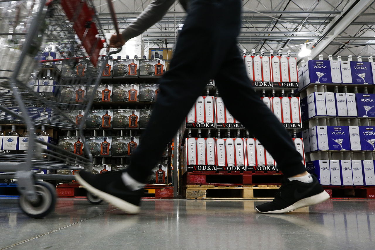 A Costco customer walks past cases of vodka and other liquors at the chain’s Lynnwood location