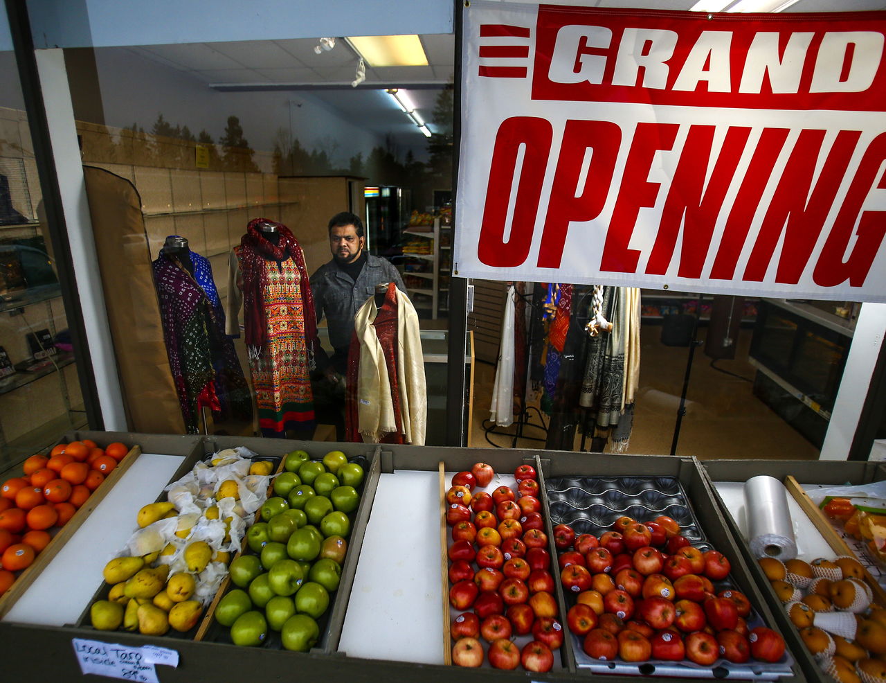 Seen through his store’s front window, co-owner, Akbar Quadri works with a small clothing display in one corner of Paradise Market, at 23204 57th Ave. W in Mountlake Terrace.