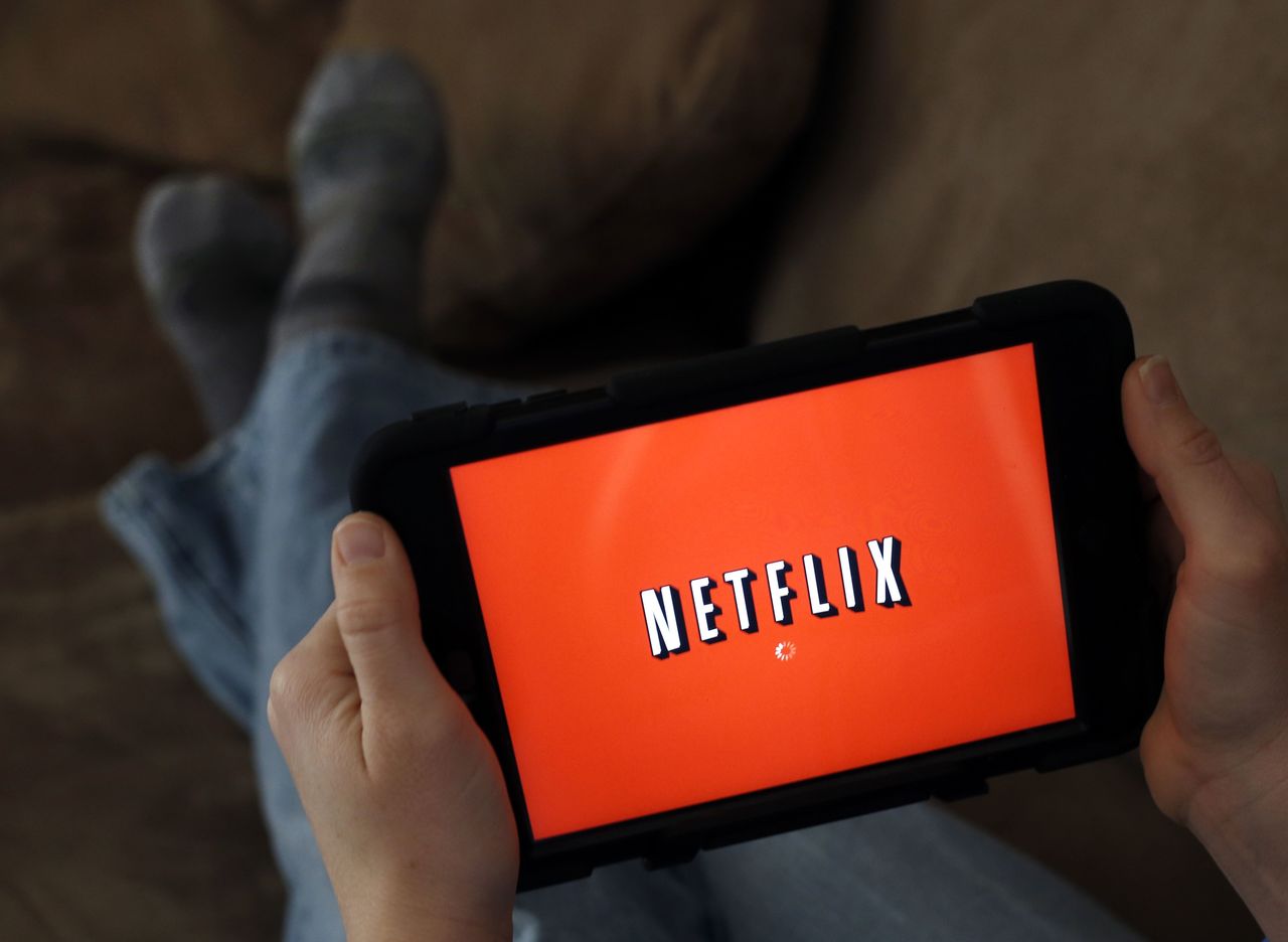 In this 2014 photo, a person displays Netflix on a tablet in North Andover, Massachusetts. Amazon is taking on Netflix and Hulu with a stand-alone video streaming service.