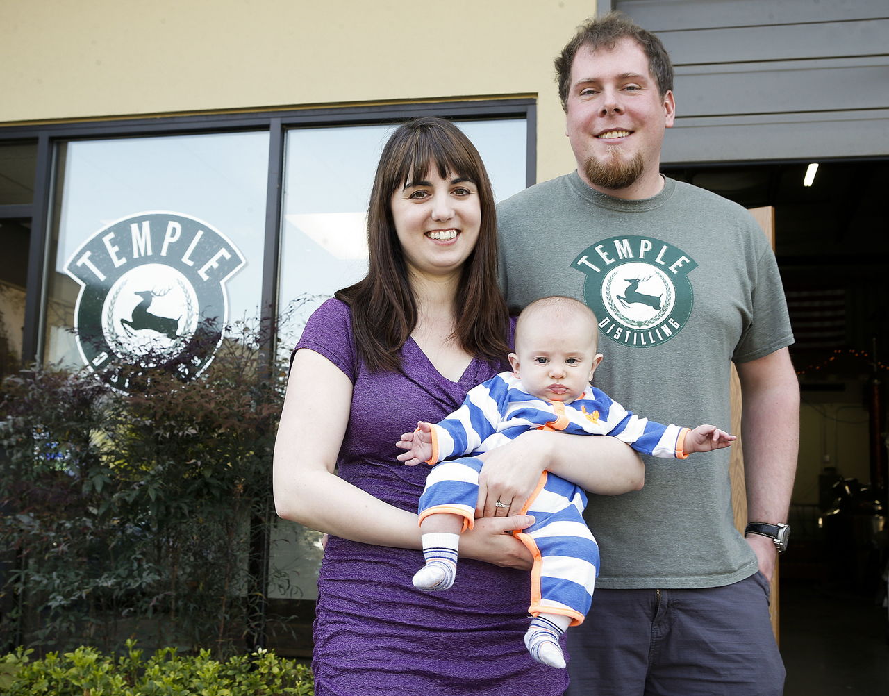 Temple Distilling owners AJ and Jamie Temple, of Bothell, hold their 4-month old son Thomas at the couple’s Lynnwood distillery.