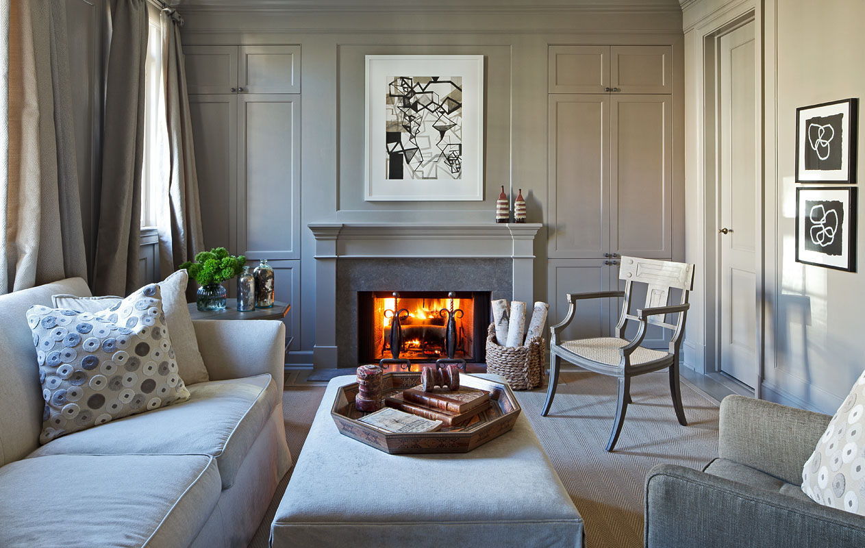 A fire crackles in a gray family room in a townhouse designed by Mary Douglas Drysdale.