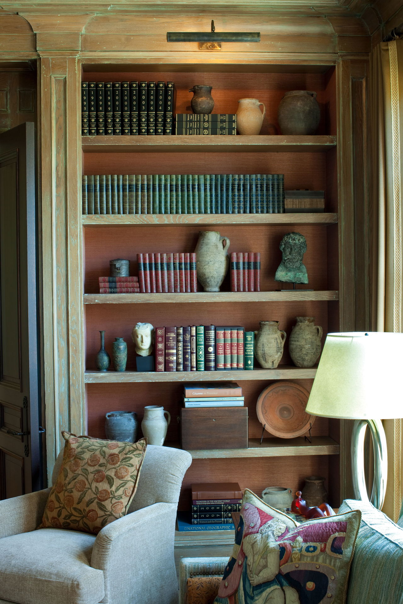 For a house in Potomac, Md., Jose Solis Betancourt and Paul Sherrill chose a copper-colored grasscloth from Maya Romanoff to set off this collection of books, ceramics and sculptures.