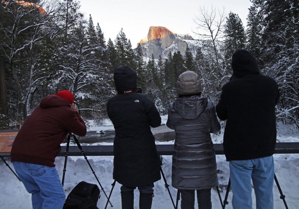 Photography enthusiasts line up along Sentinel Bridge in Yosemite Valley to photograph the alpenglow of the sunset hitting Half Dome.
