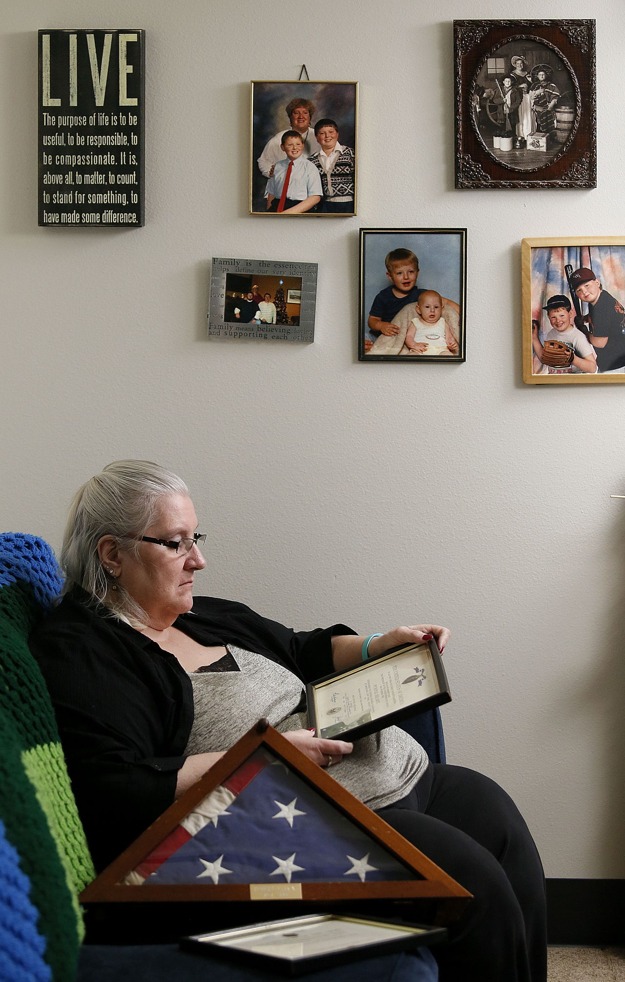 Sitting beneath her family photos in her Everett apartment, Diane Lucas, 56, reads the certification of the Purple Heart awarded by the President of the United States to her late husband, Robert, a Vietnam War veteran. It was rescued from the trash in Iowa at a storage rental unit.