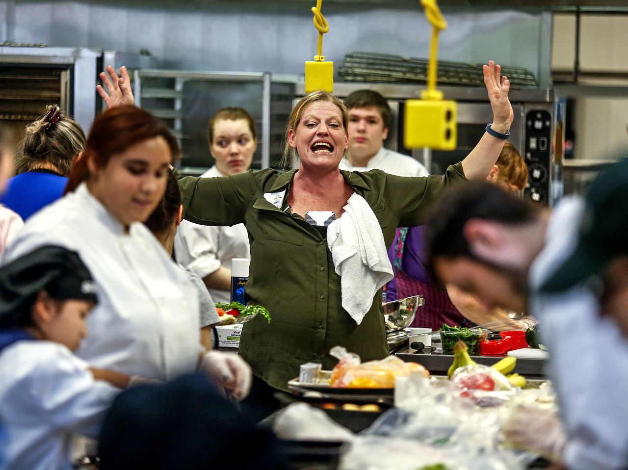 Event coordinator, Mo Wolf, center, hollers out to all the contestants that it is time to take their finished entries to be garnished and placed on a black plate by “Chef Jim!”