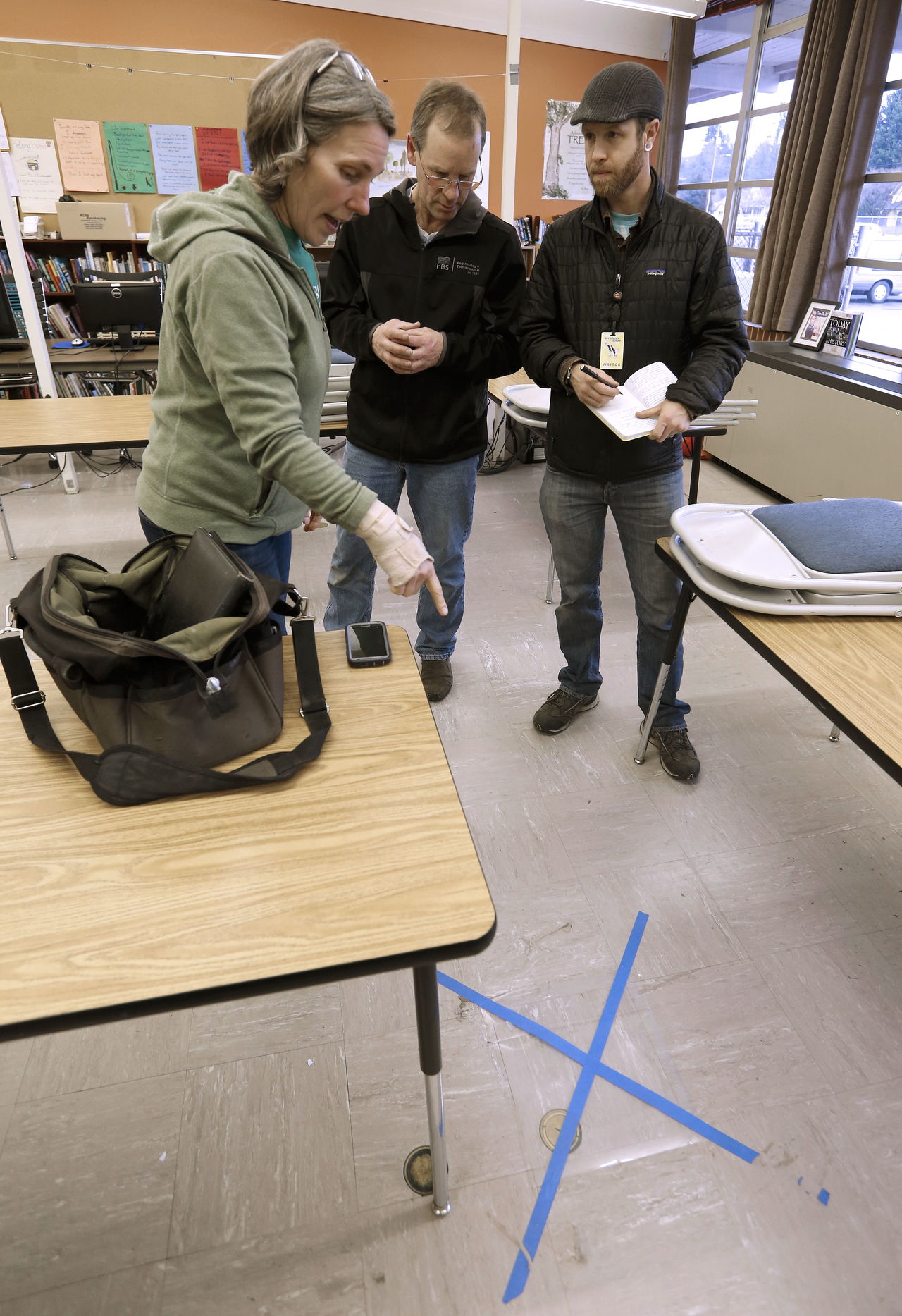 Teacher Heidi Engle helps pinpoint an area of a stain as Gregg Middaugh and Kevin Hood, from PBS Engineering + Environmental, take notes Jan. 26 at a classroom at Sky Valley Education Center in Monroe. The trio then marked the spot so a swipe sample could be taken and analyzed to see if there was contamination that could be causing some students and staff to become sick.