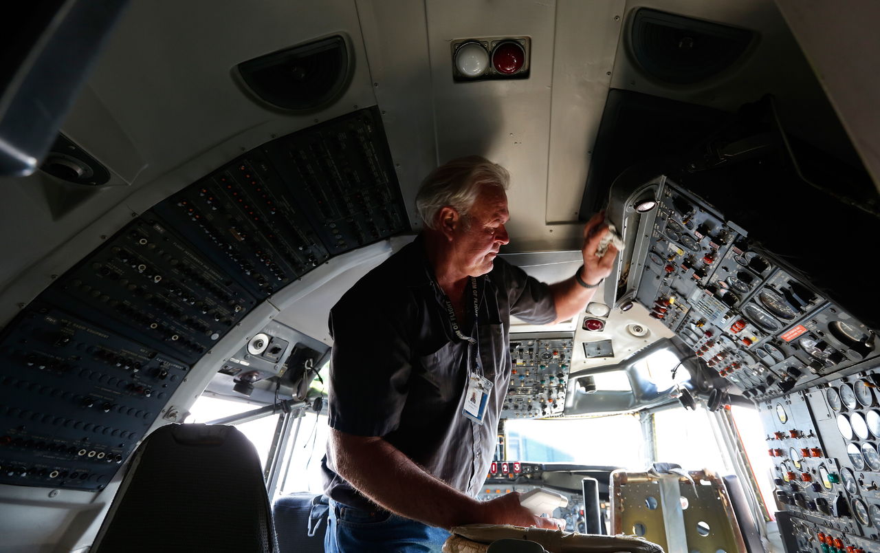 Volunteer Jim Munneke wipes down surfaces in the cockpit of the prototype 727 at Paine Field on Thursday. The plane is expected to make its final flight to Boeing Field on Tuesday, where it will end up in the Boeing Museum of Flight.
