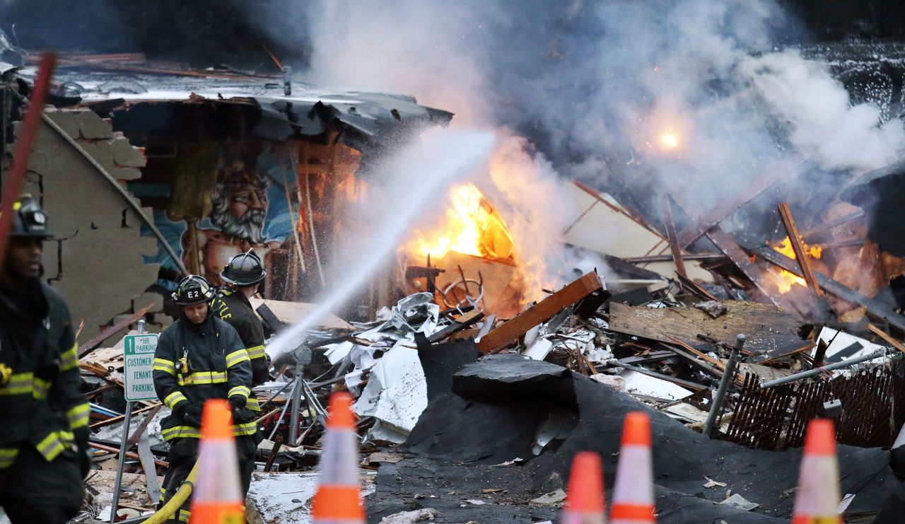 Firefighters pour water on flames burn in the rubble of an early morning explosion Wednesday in Seattle.