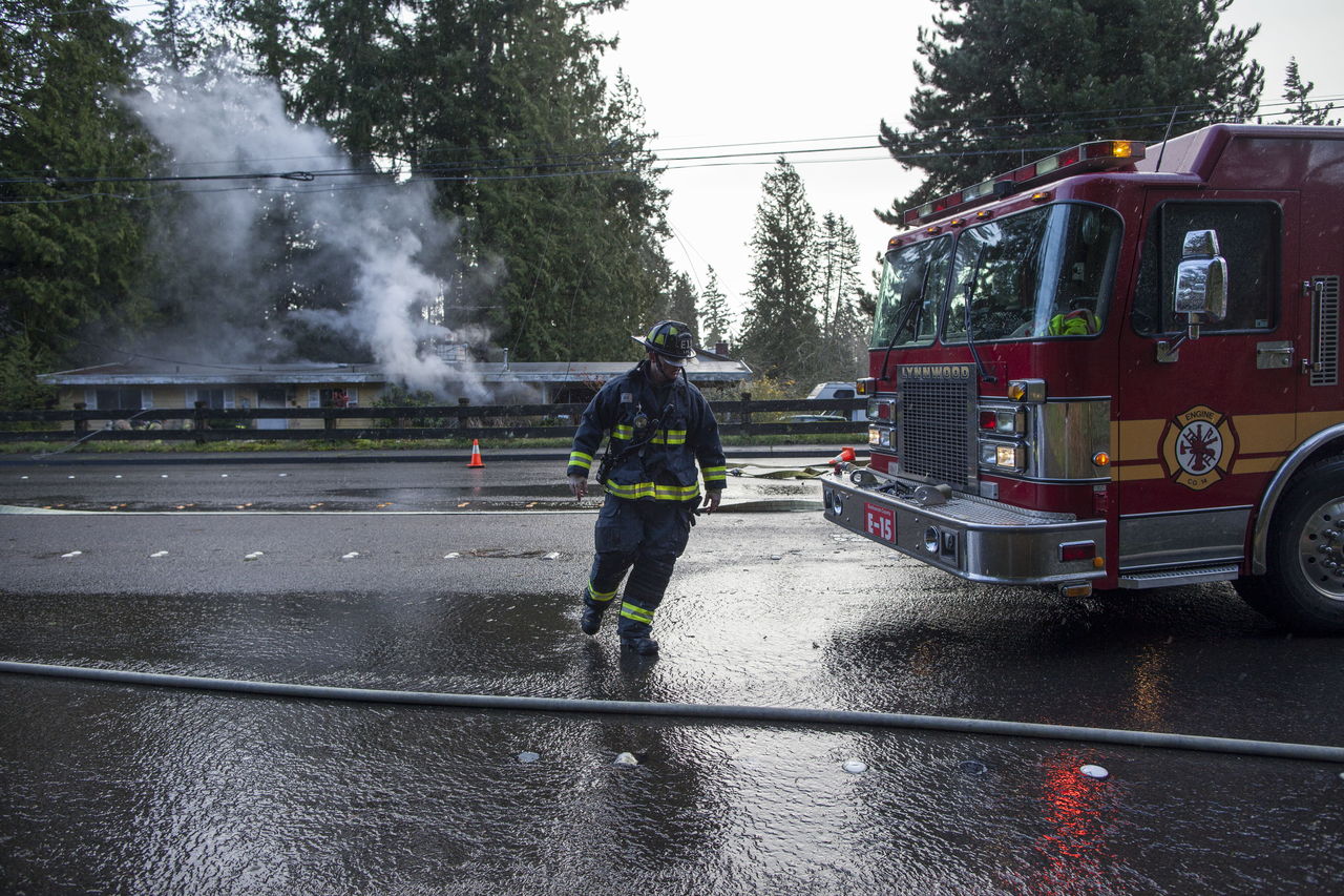 Firefighters work on one of two fires started when a tall fir fell across 36th Avenue near Maple Street, causing house fires on both sides of the street.